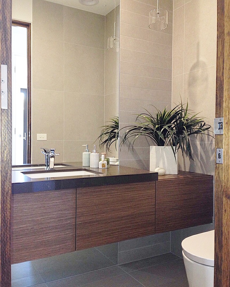 Photo of a small modern cloakroom in Melbourne with a wall mounted toilet, a submerged sink, engineered stone worktops and grey tiles.