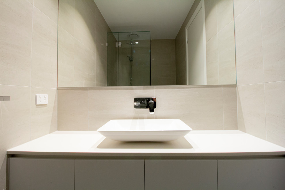 Kleine Moderne Gästetoilette mit Lamellenschränken, weißen Schränken, Toilette mit Aufsatzspülkasten, beigen Fliesen, Keramikfliesen, Keramikboden, Aufsatzwaschbecken, Beton-Waschbecken/Waschtisch, grauem Boden und weißer Waschtischplatte in Melbourne