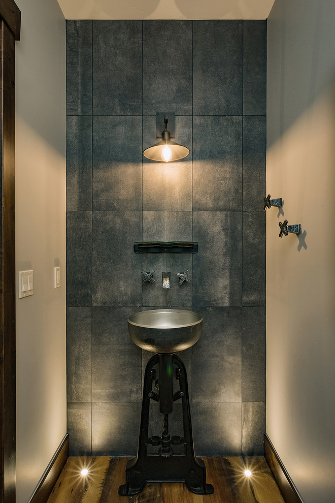 Foto di un piccolo bagno di servizio rustico con piastrelle grigie, piastrelle in pietra, pavimento in legno massello medio, lavabo a colonna e pavimento marrone