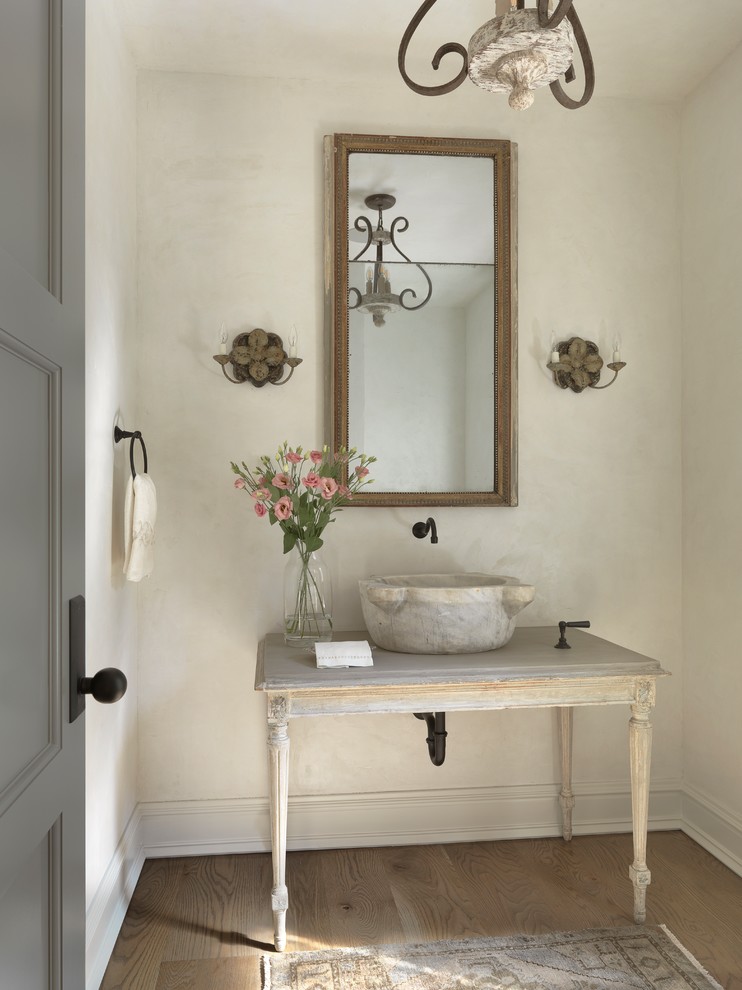 Shabby-Look Gästetoilette mit verzierten Schränken, Schränken im Used-Look, beiger Wandfarbe, hellem Holzboden, Aufsatzwaschbecken und grauer Waschtischplatte in Sonstige
