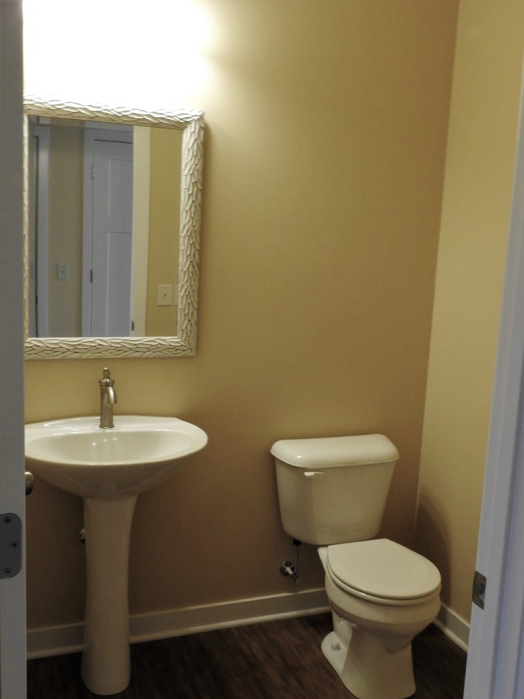 Cette photo montre un petit WC et toilettes craftsman avec WC séparés, un mur jaune, sol en stratifié, un lavabo de ferme et un sol beige.