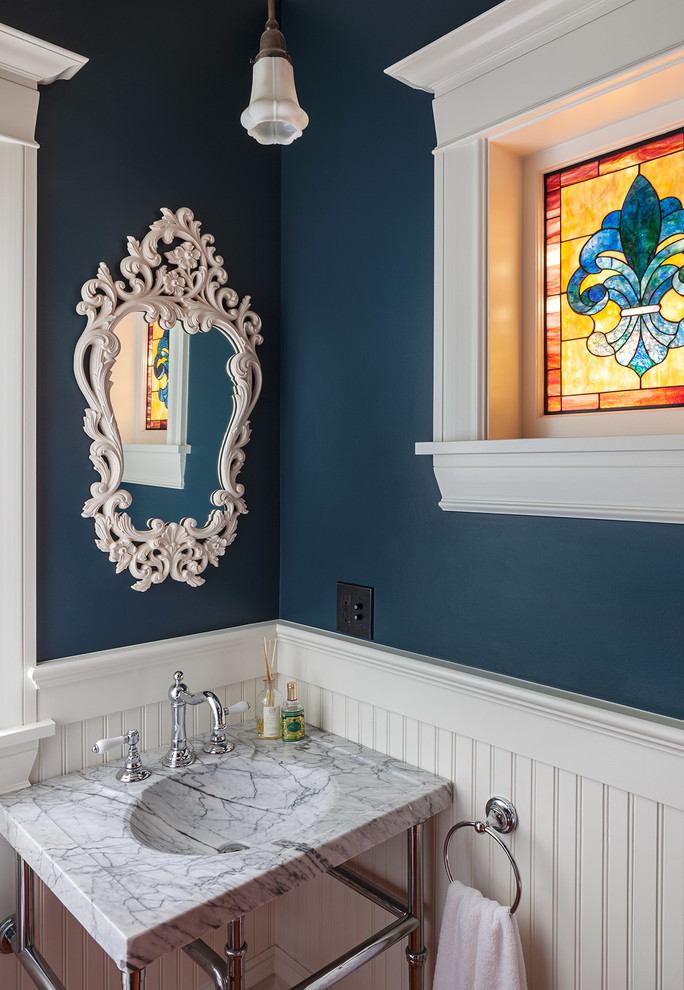 Klassisk inredning av ett litet grå grått toalett, med blå väggar, ett konsol handfat och marmorbänkskiva
