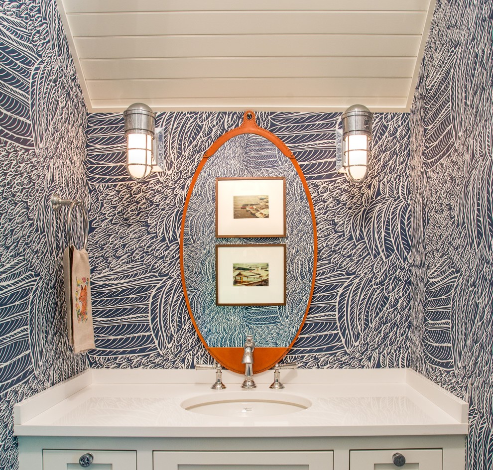 Example of a small trendy powder room design in Other with recessed-panel cabinets, white cabinets, blue walls, an undermount sink, solid surface countertops and white countertops