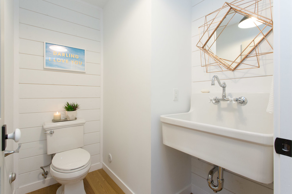 На фото: маленький туалет в морском стиле с белыми стенами, подвесной раковиной, раздельным унитазом, паркетным полом среднего тона и оранжевым полом для на участке и в саду