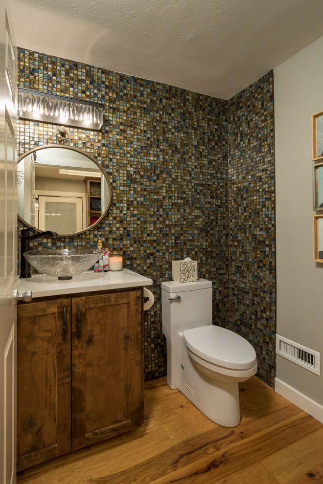 Inspiration for a small classic cloakroom in Dallas with recessed-panel cabinets, medium wood cabinets, a one-piece toilet, multi-coloured tiles, glass tiles, beige walls, medium hardwood flooring, a vessel sink, engineered stone worktops, brown floors and yellow worktops.
