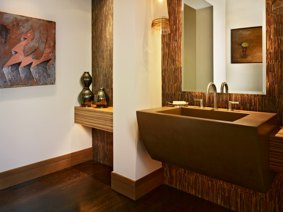 Свежая идея для дизайна: туалет среднего размера в современном стиле с монолитной раковиной, коричневой плиткой, удлиненной плиткой, белыми стенами, темным паркетным полом и столешницей из искусственного камня - отличное фото интерьера