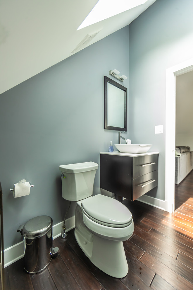 Immagine di un bagno di servizio american style di medie dimensioni con ante lisce, ante in legno bruno, WC a due pezzi, pareti blu, parquet scuro, lavabo a bacinella, top in superficie solida, pavimento marrone e top bianco