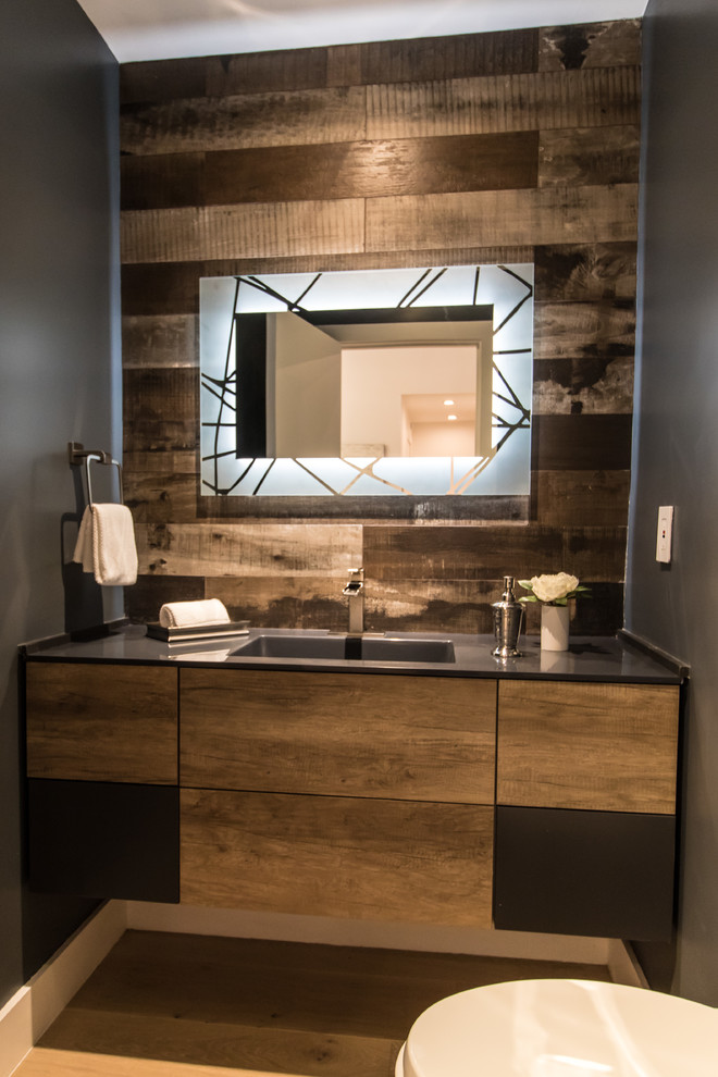Example of a mid-sized minimalist porcelain tile medium tone wood floor and brown floor powder room design in Los Angeles with flat-panel cabinets, medium tone wood cabinets, a two-piece toilet, gray walls, a drop-in sink, solid surface countertops and gray countertops
