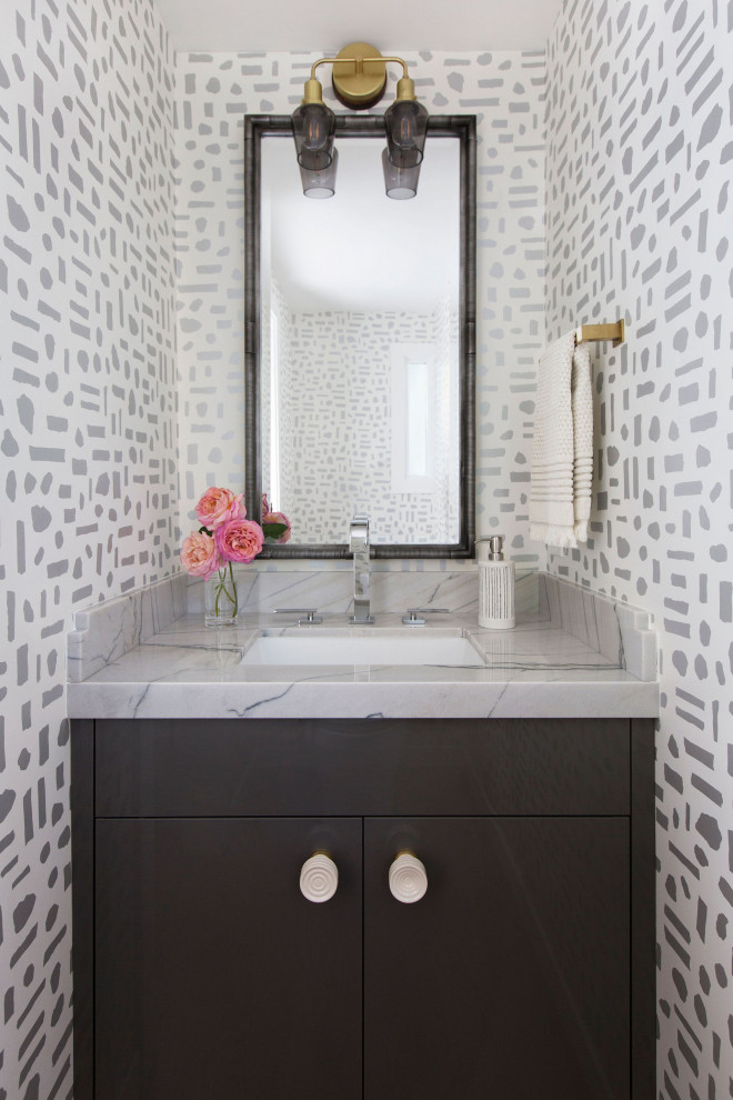 Foto på ett litet funkis grå toalett, med släta luckor, grå skåp, vita väggar, mellanmörkt trägolv, ett undermonterad handfat och marmorbänkskiva