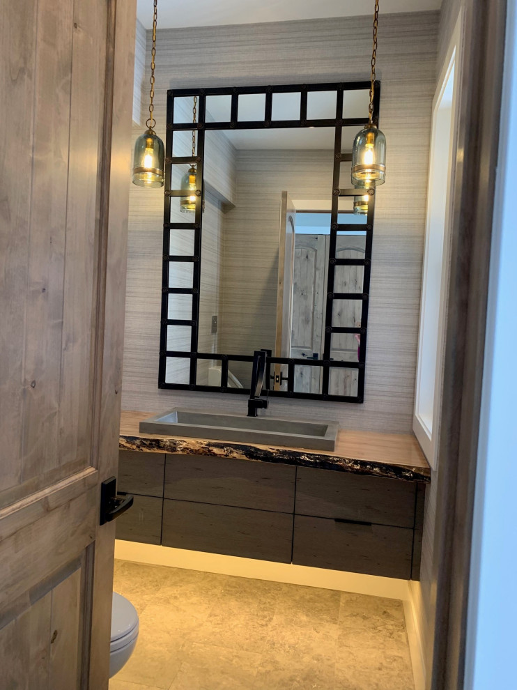 Small eclectic cloakroom in Chicago with flat-panel cabinets, medium wood cabinets, a one-piece toilet, grey walls, limestone flooring, a built-in sink, wooden worktops, grey floors, brown worktops, a floating vanity unit and wallpapered walls.