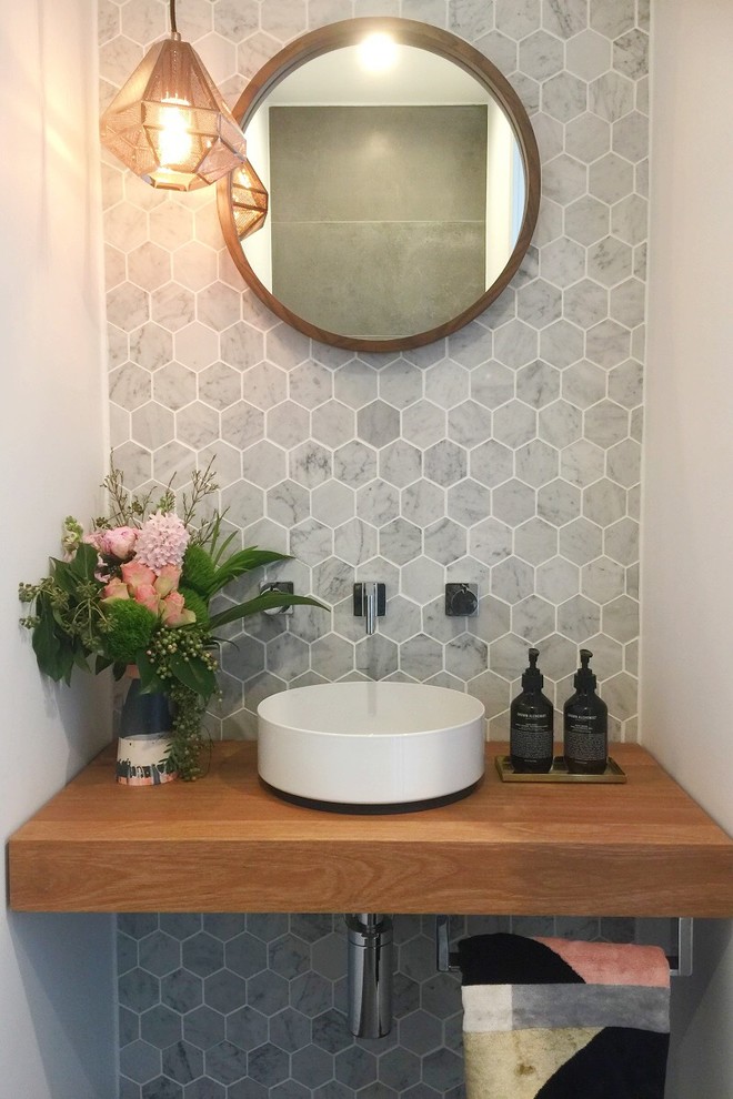 Small modern cloakroom in Canberra - Queanbeyan with a wall mounted toilet, grey tiles, marble tiles, white walls, porcelain flooring, a vessel sink, wooden worktops, grey floors and brown worktops.
