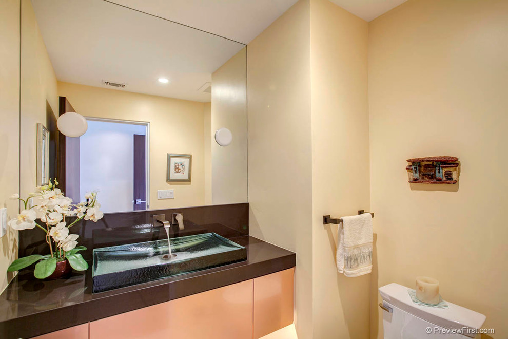 Aménagement d'un WC et toilettes contemporain en bois brun de taille moyenne avec une vasque, un placard à porte plane, WC à poser et un mur beige.