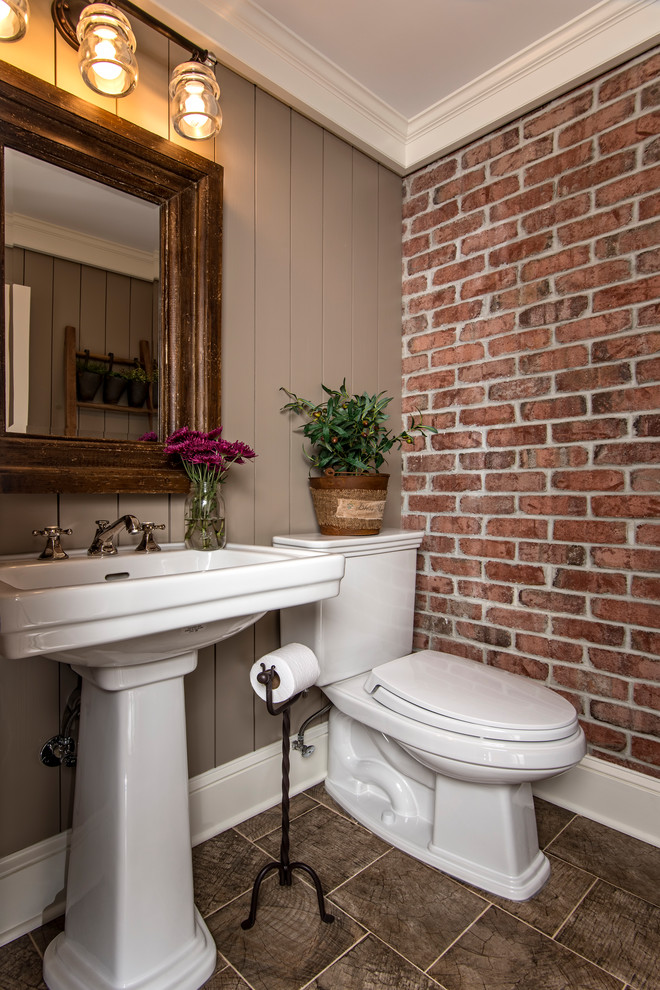 ニューヨークにあるカントリー風のおしゃれなトイレ・洗面所 (分離型トイレ、グレーの壁、ペデスタルシンク、茶色い床) の写真