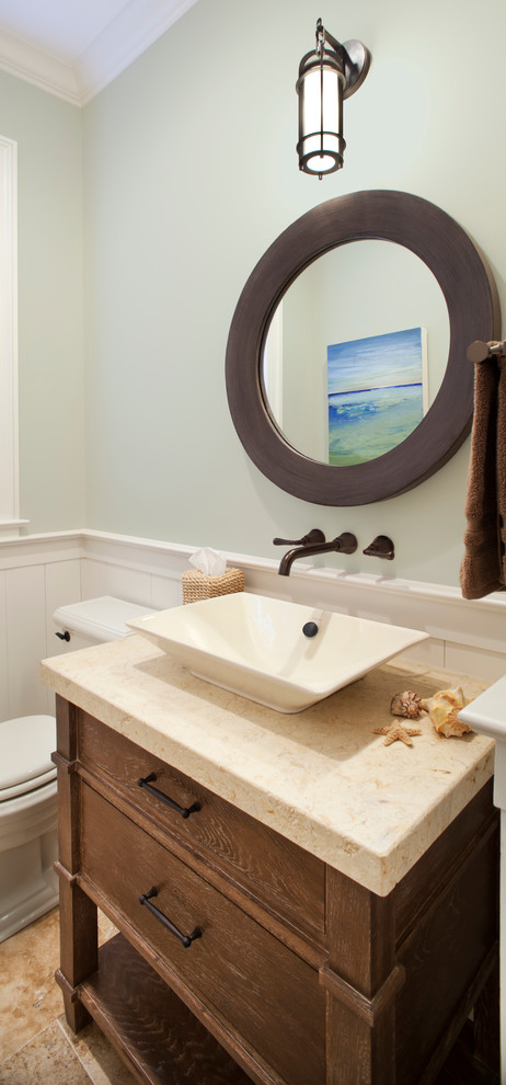 Cette photo montre un WC et toilettes bord de mer en bois brun avec un placard en trompe-l'oeil, un mur vert, un sol en travertin, une vasque et un plan de toilette en calcaire.