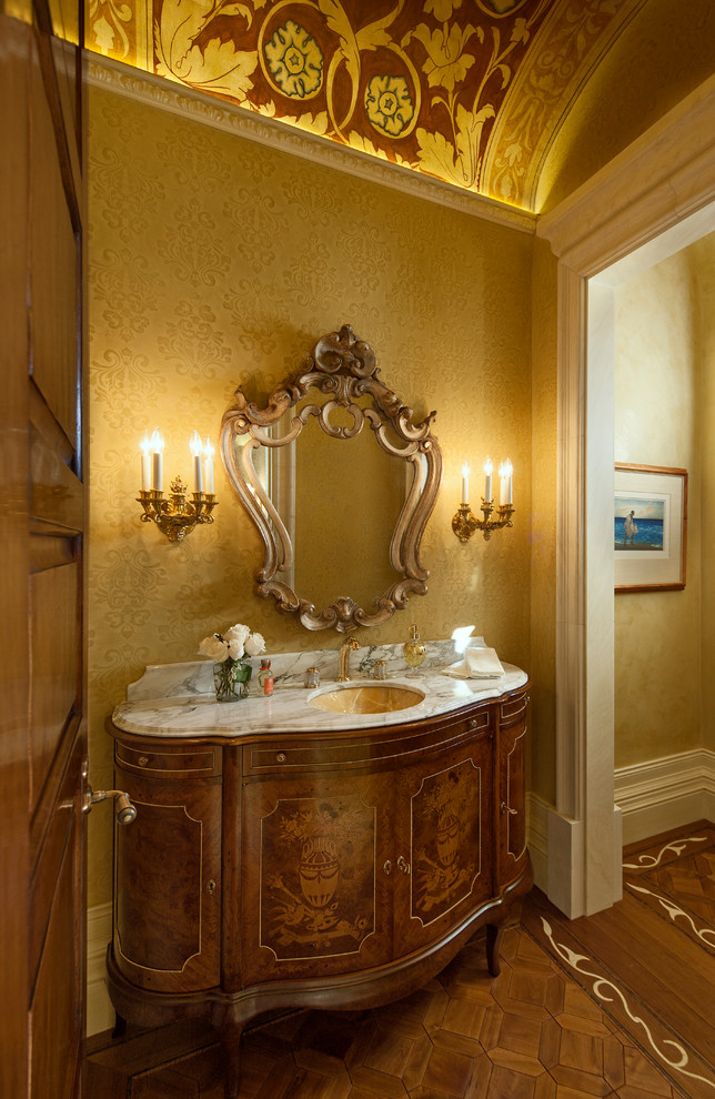 Esempio di un bagno di servizio mediterraneo con lavabo sottopiano, consolle stile comò, ante in legno bruno, top in marmo e top bianco