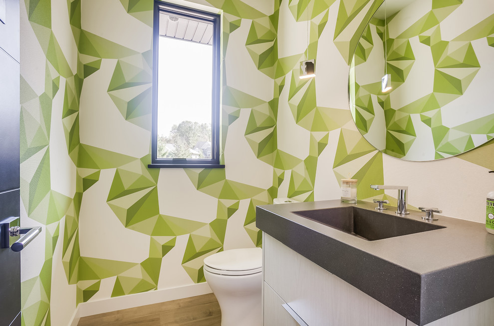 Inspiration för moderna grått toaletter, med släta luckor, vita skåp, gröna väggar, mellanmörkt trägolv, ett integrerad handfat och brunt golv