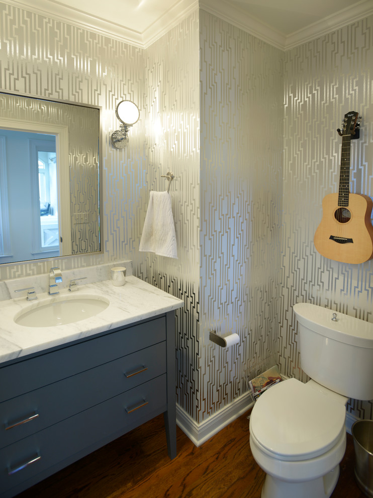 Inspiration för klassiska vitt toaletter, med ett undermonterad handfat, grå skåp, en toalettstol med separat cisternkåpa, flerfärgade väggar, mellanmörkt trägolv och släta luckor
