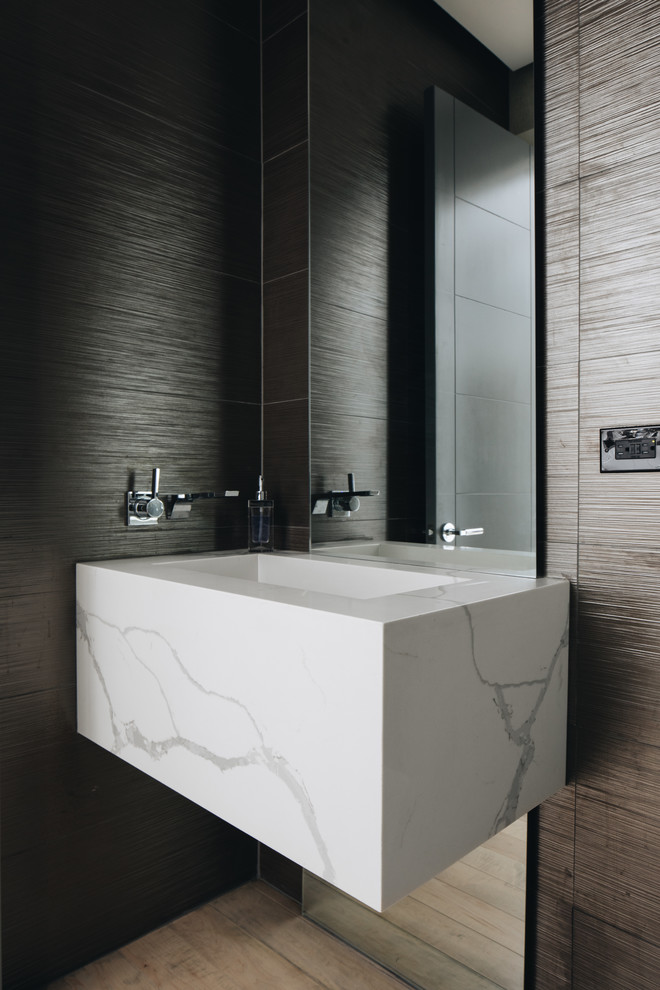 This is an example of a small contemporary cloakroom in Chicago with a wall mounted toilet, multi-coloured tiles, porcelain tiles, light hardwood flooring, a wall-mounted sink, engineered stone worktops and white worktops.