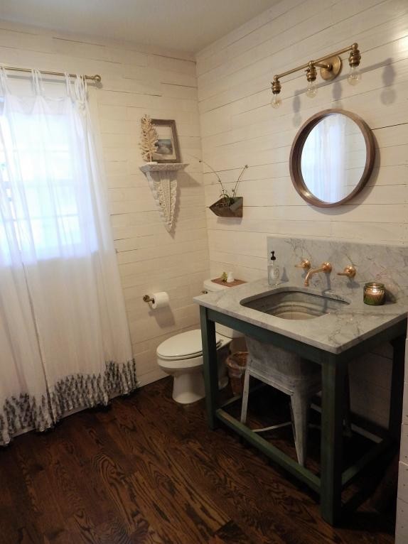 Powder room - mid-sized country dark wood floor and brown floor powder room idea in St Louis with furniture-like cabinets, distressed cabinets, a two-piece toilet, white walls, marble countertops and a console sink