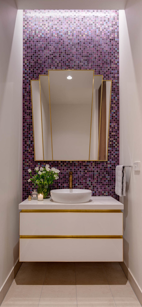 Cette image montre un WC et toilettes design de taille moyenne avec un placard à porte plane, des portes de placard blanches, un carrelage multicolore, mosaïque, un mur violet, un sol en carrelage de céramique, une vasque, un plan de toilette en quartz modifié et un sol beige.