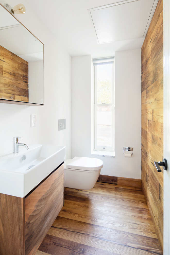 Foto di un bagno di servizio minimal con ante lisce, ante in legno scuro, WC sospeso, pareti bianche, pavimento in legno massello medio, lavabo a consolle e pavimento marrone