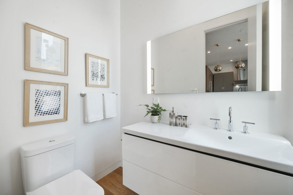 Medium sized contemporary cloakroom in San Francisco with flat-panel cabinets, white cabinets, a one-piece toilet, white walls, medium hardwood flooring, an integrated sink, solid surface worktops, brown floors, white worktops and a floating vanity unit.