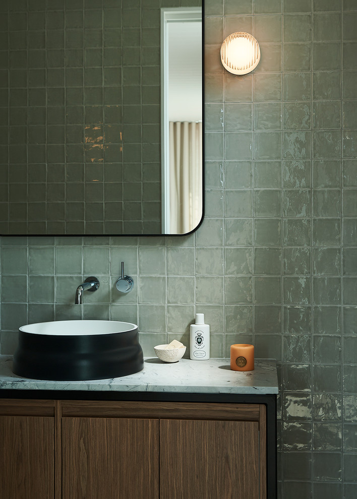Idee per un bagno di servizio minimal con ante lisce, ante in legno scuro, piastrelle grigie, pareti grigie, lavabo a bacinella, top in marmo e top bianco