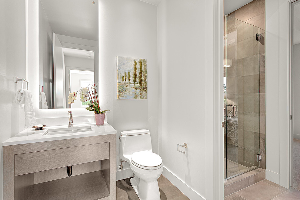 Cette image montre un WC et toilettes design en bois clair de taille moyenne avec un placard sans porte, WC à poser, un carrelage beige, des carreaux de béton, un mur blanc, un sol en carrelage de céramique, un lavabo encastré, un plan de toilette en calcaire et un sol beige.