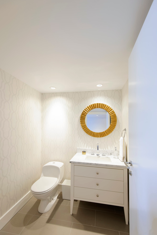 Exemple d'un petit WC et toilettes tendance avec un lavabo encastré, un placard en trompe-l'oeil, des portes de placard blanches, un plan de toilette en marbre, WC à poser, un carrelage gris et un sol en carrelage de porcelaine.
