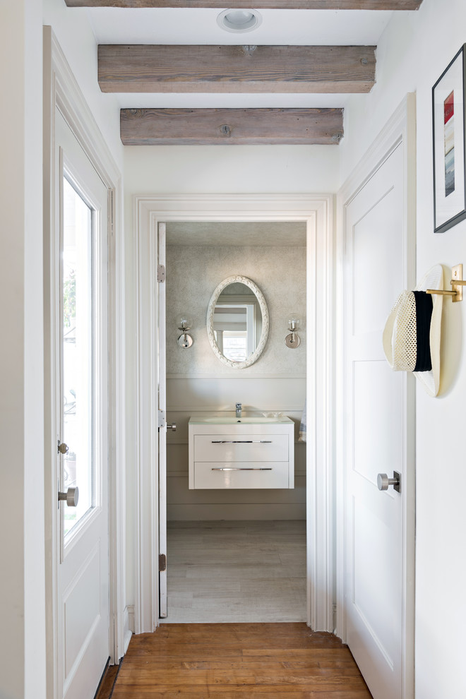 Inspiration for a nautical cloakroom in Boston with flat-panel cabinets, white cabinets, beige walls, beige floors and a console sink.