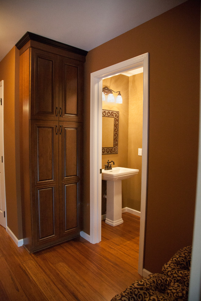 Esempio di un bagno di servizio tradizionale con lavabo a colonna, ante con bugna sagomata, ante in legno scuro e pareti marroni