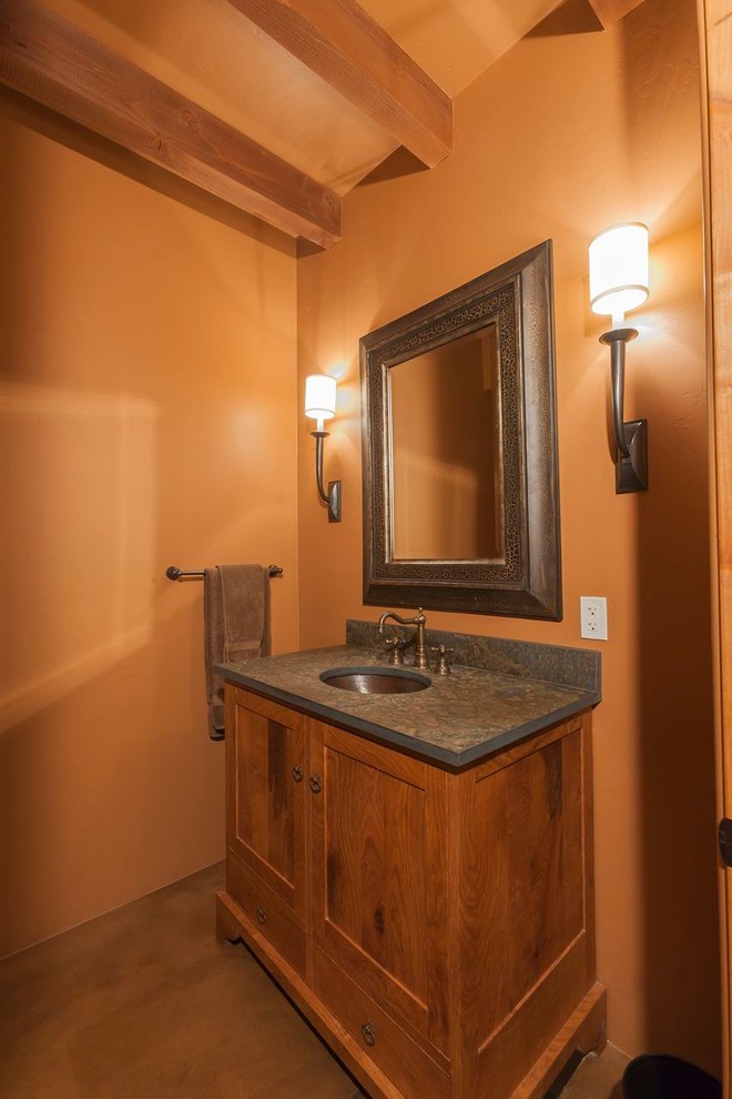 Idées déco pour un petit WC et toilettes classique en bois brun avec un lavabo encastré, un mur orange, sol en béton ciré et un placard avec porte à panneau encastré.