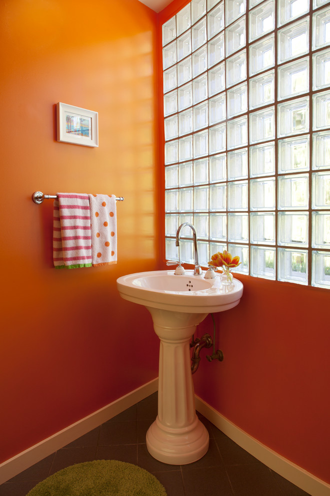 Maritim inredning av ett toalett, med ett piedestal handfat och orange väggar