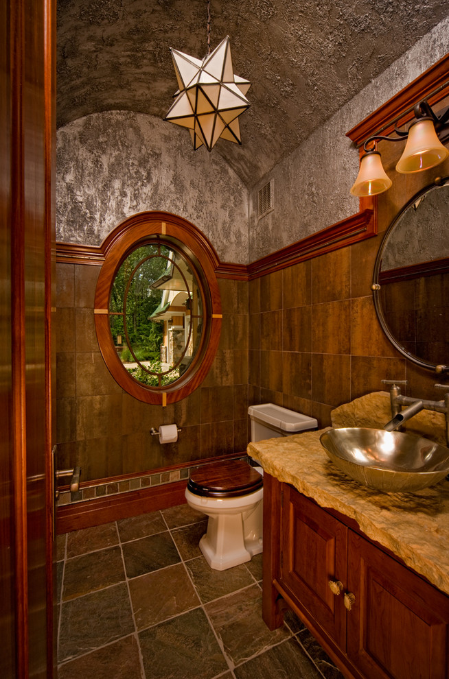 Стильный дизайн: туалет среднего размера: освещение в стиле рустика с настольной раковиной, фасадами с выступающей филенкой, коричневой плиткой, серыми стенами, темными деревянными фасадами и коричневой столешницей - последний тренд
