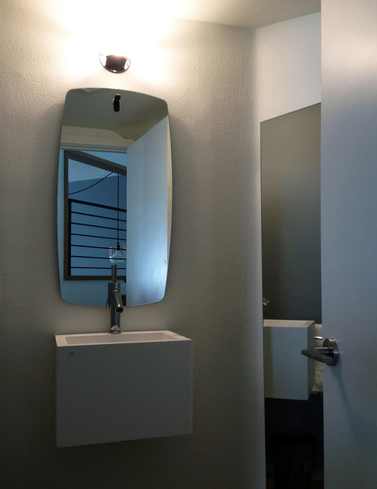 Modelo de aseo retro pequeño con lavabo suspendido, armarios tipo mueble, puertas de armario blancas, paredes grises, sanitario de dos piezas y suelo de madera en tonos medios