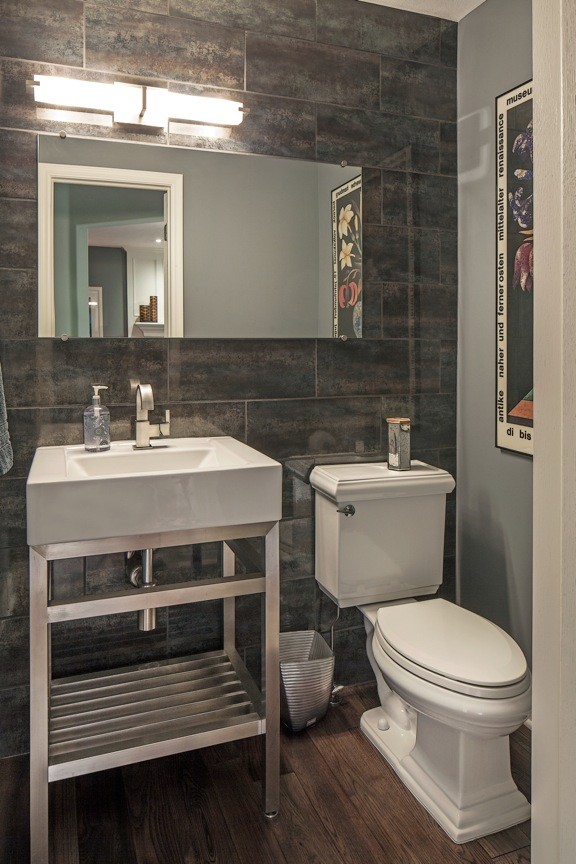Photo of a medium sized classic cloakroom in Omaha with a pedestal sink, grey walls, dark hardwood flooring, open cabinets, a two-piece toilet, brown tiles, grey tiles, porcelain tiles, solid surface worktops and brown floors.
