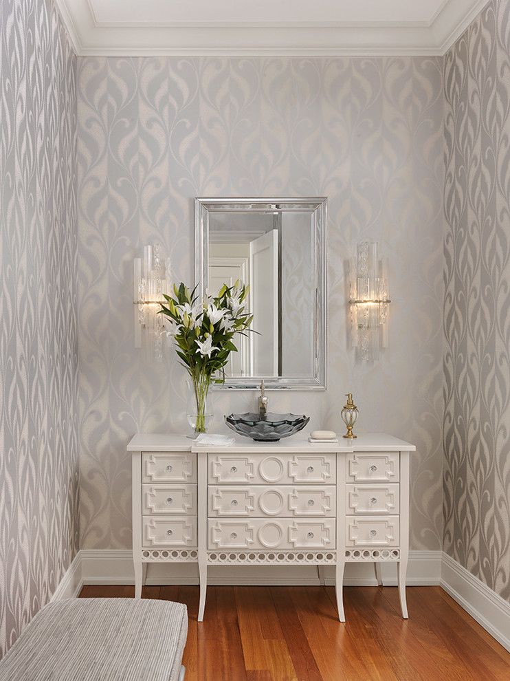 Inredning av ett klassiskt mellanstort vit vitt toalett, med möbel-liknande, vita skåp, mellanmörkt trägolv, ett fristående handfat och flerfärgade väggar