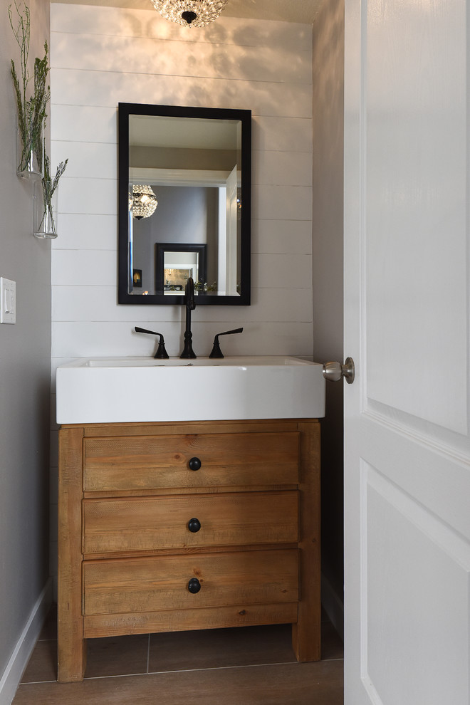 フェニックスにある小さなカントリー風のおしゃれなトイレ・洗面所 (フラットパネル扉のキャビネット、茶色いキャビネット、グレーの壁、無垢フローリング、一体型シンク、茶色い床) の写真