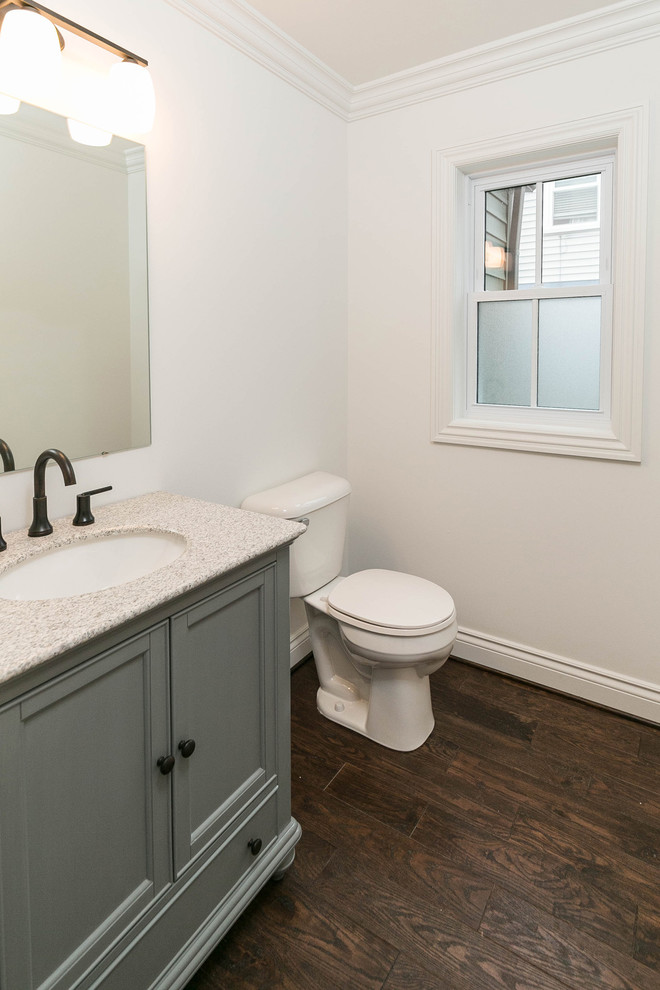 Inspiration för små klassiska toaletter, med möbel-liknande, gröna skåp, en toalettstol med separat cisternkåpa, vit kakel, vita väggar, mörkt trägolv, ett undermonterad handfat, granitbänkskiva och brunt golv