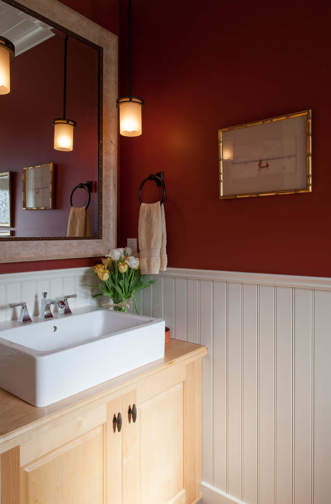 Idee per un bagno di servizio tradizionale con lavabo a bacinella, ante con bugna sagomata, ante in legno chiaro, top in legno, WC monopezzo, pareti rosse e pavimento in legno massello medio