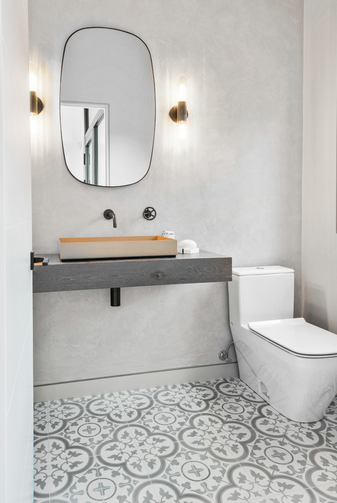 ニューヨークにあるインダストリアルスタイルのおしゃれなトイレ・洗面所 (一体型トイレ	、磁器タイルの床、ベッセル式洗面器) の写真