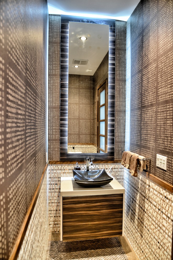 Пример оригинального дизайна: большой туалет в современном стиле с настольной раковиной, плоскими фасадами, темными деревянными фасадами, столешницей из искусственного камня, бежевой плиткой, коричневыми стенами, полом из мозаичной плитки, плиткой мозаикой и белой столешницей