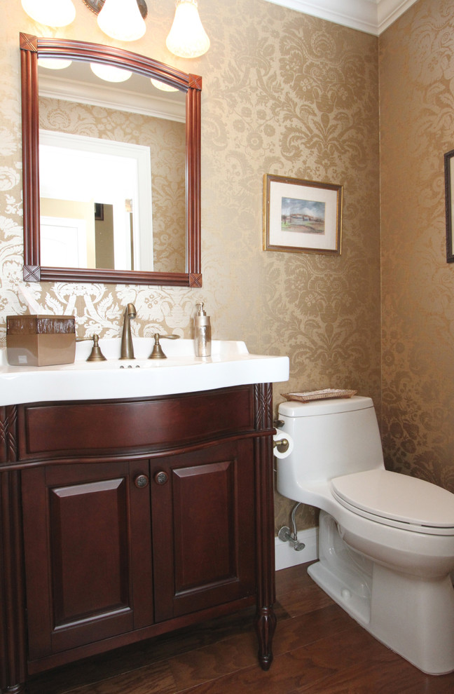 Aménagement d'un petit WC et toilettes classique en bois foncé avec un placard avec porte à panneau surélevé, parquet foncé, un lavabo intégré et un plan de toilette en surface solide.