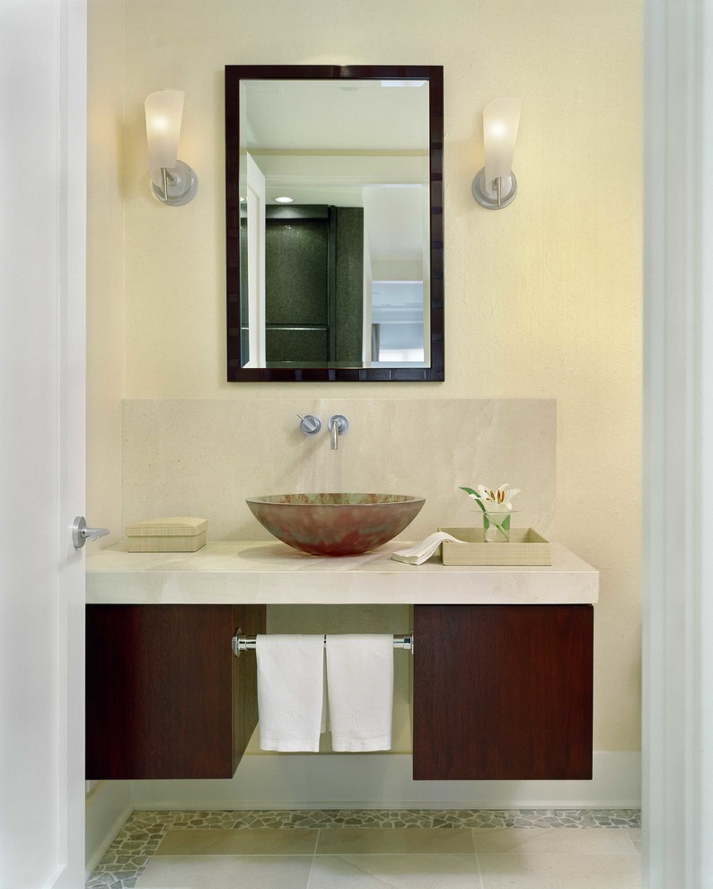 Idee per un bagno di servizio minimal con lavabo a bacinella, ante lisce, ante in legno scuro, pareti beige, pavimento con piastrelle di ciottoli, top in marmo e pavimento beige
