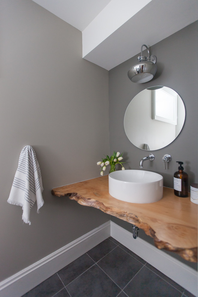 Inspiration pour un grand WC et toilettes design en bois brun avec un carrelage gris, un mur gris, un sol en carrelage de porcelaine, une vasque, un plan de toilette en bois, un placard sans porte, un sol gris et un plan de toilette marron.