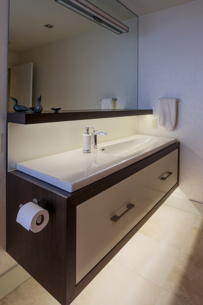 Cette image montre un WC et toilettes design de taille moyenne avec un placard à porte plane, des portes de placard blanches, WC à poser, un mur blanc, un sol en carrelage de céramique et un lavabo intégré.
