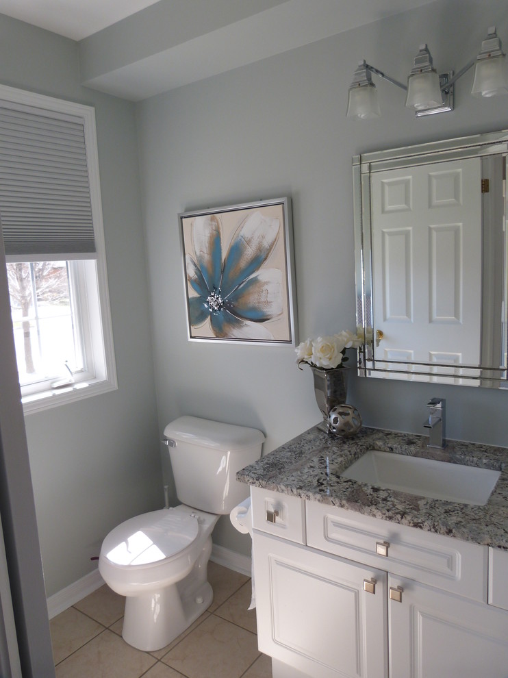 Immagine di un piccolo bagno di servizio design con ante con bugna sagomata, ante bianche, lavabo sottopiano, top in granito e top grigio