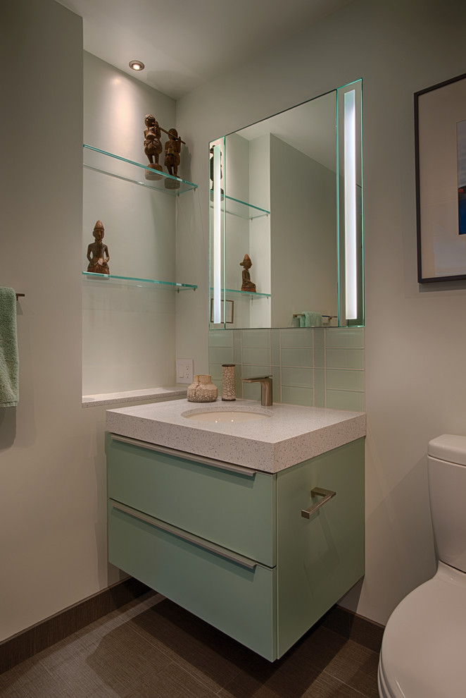 Photo of a contemporary cloakroom in San Francisco with flat-panel cabinets, green cabinets, engineered stone worktops, multi-coloured tiles, glass tiles, white walls, porcelain flooring, a one-piece toilet and a submerged sink.