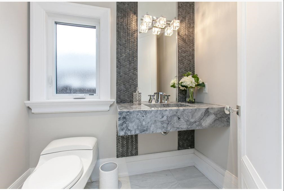 Powder room - mid-sized contemporary gray tile and stone tile ceramic tile and white floor powder room idea in Toronto with a wall-mount toilet, gray walls, an integrated sink, marble countertops and gray countertops