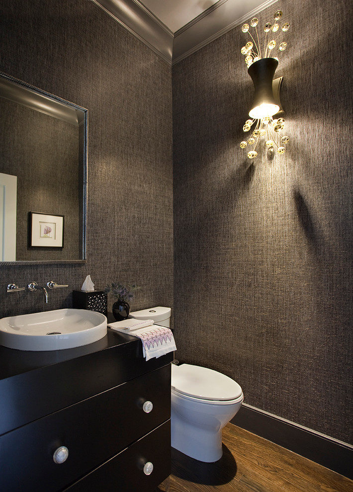 This is an example of a medium sized contemporary cloakroom in Boston with flat-panel cabinets, dark wood cabinets, a one-piece toilet, grey walls, medium hardwood flooring and a vessel sink.